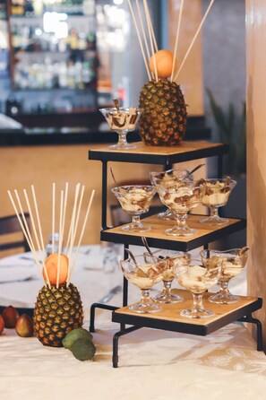 A dessert display with multiple tiers, including a pineapple and various desserts in glass dishes. - Highlands Suites Hotel (Kigali)