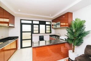 A modern kitchen with wooden cabinets, a black countertop, and a large window. - Highlands Suites Hotel (Kigali)