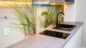 A modern kitchen with a built-in sink, a black faucet, and a glass backsplash. - Apart Hotel Residence Jastrzębia Góra (Wladyslawowo)