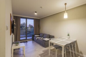 Uma sala de estar moderna com sofá, mesa de jantar e uma janela ampla.