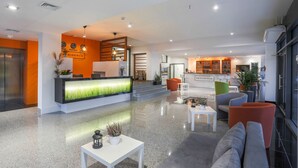 A modern hotel lobby with a reception desk, seating area, and a kitchen in the background. - Apart Hotel Residence Jastrzębia Góra (Wladyslawowo)