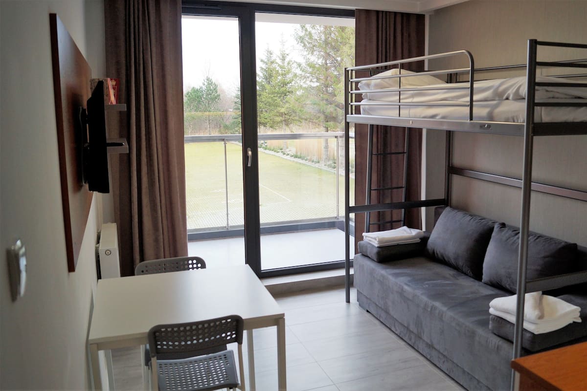 Ein Zimmer mit Etagenbett, einer Schlafcouch, einem Tisch und einem Stuhl.