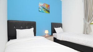 Habitación de hotel con dos camas, una mesita de noche con lámpara y un cuadro en la pared.
