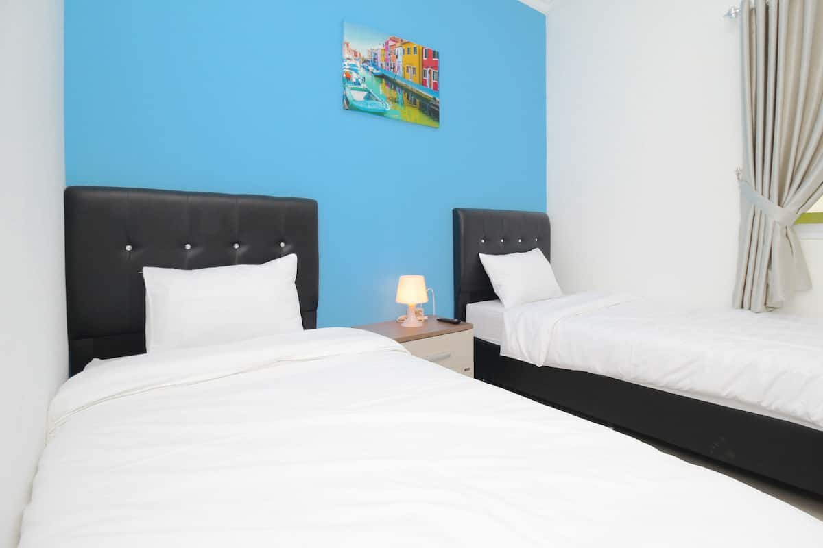 A hotel room with two beds, a nightstand with a lamp, and a painting on the wall.