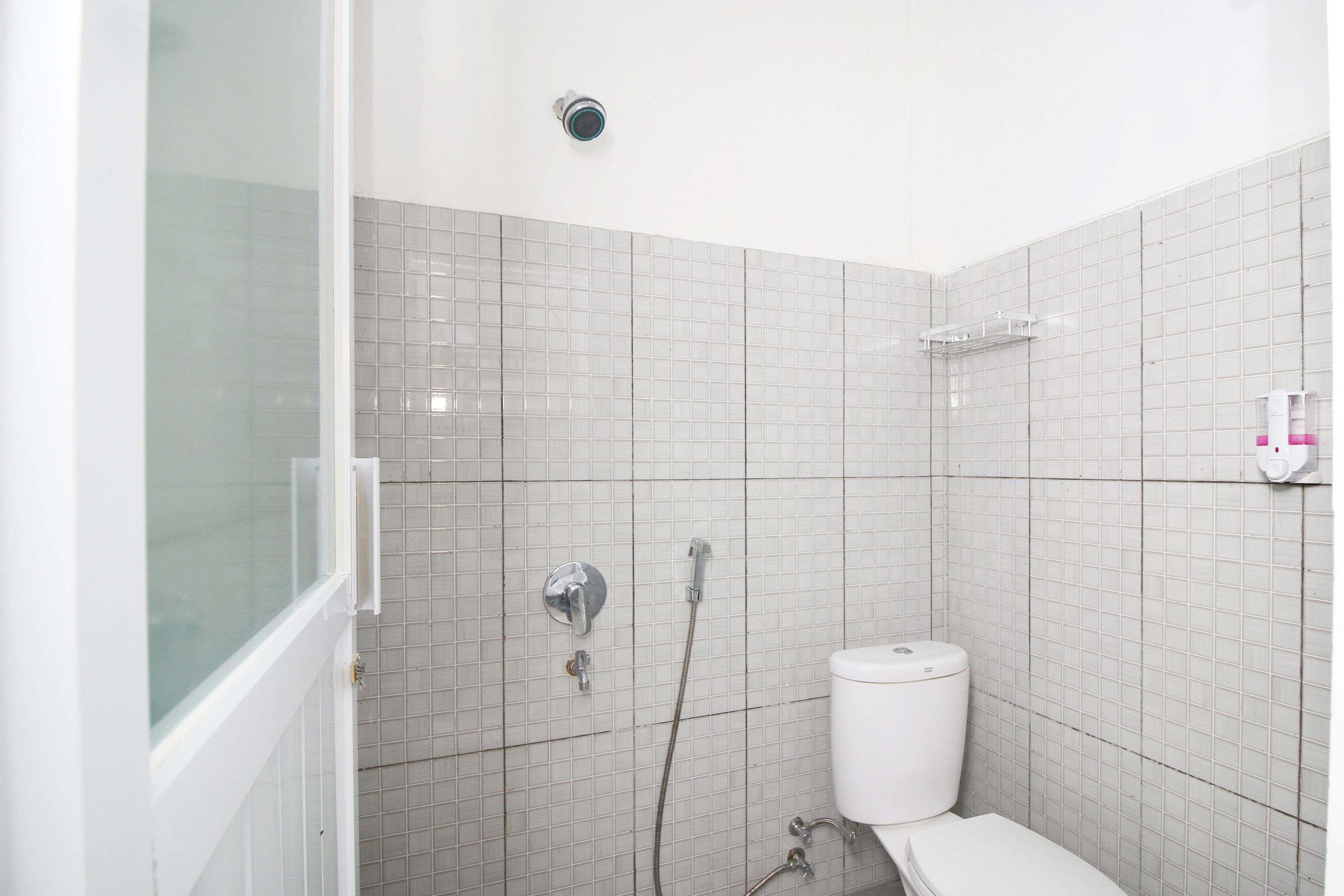 Un baño con inodoro, ducha y cabina de ducha con mampara de vidrio.