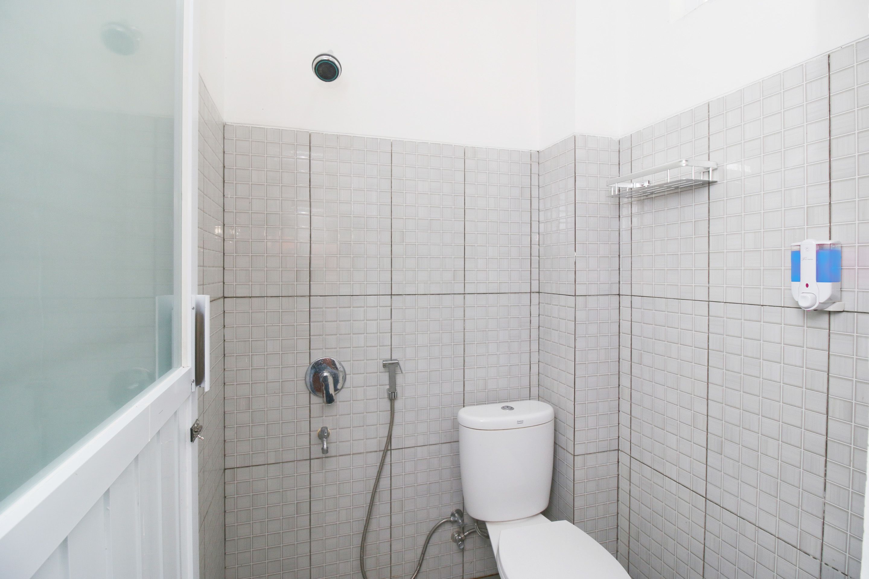 Une salle de bain comprenant des toilettes, une douche et un espace de douche fermé par des parois en verre.