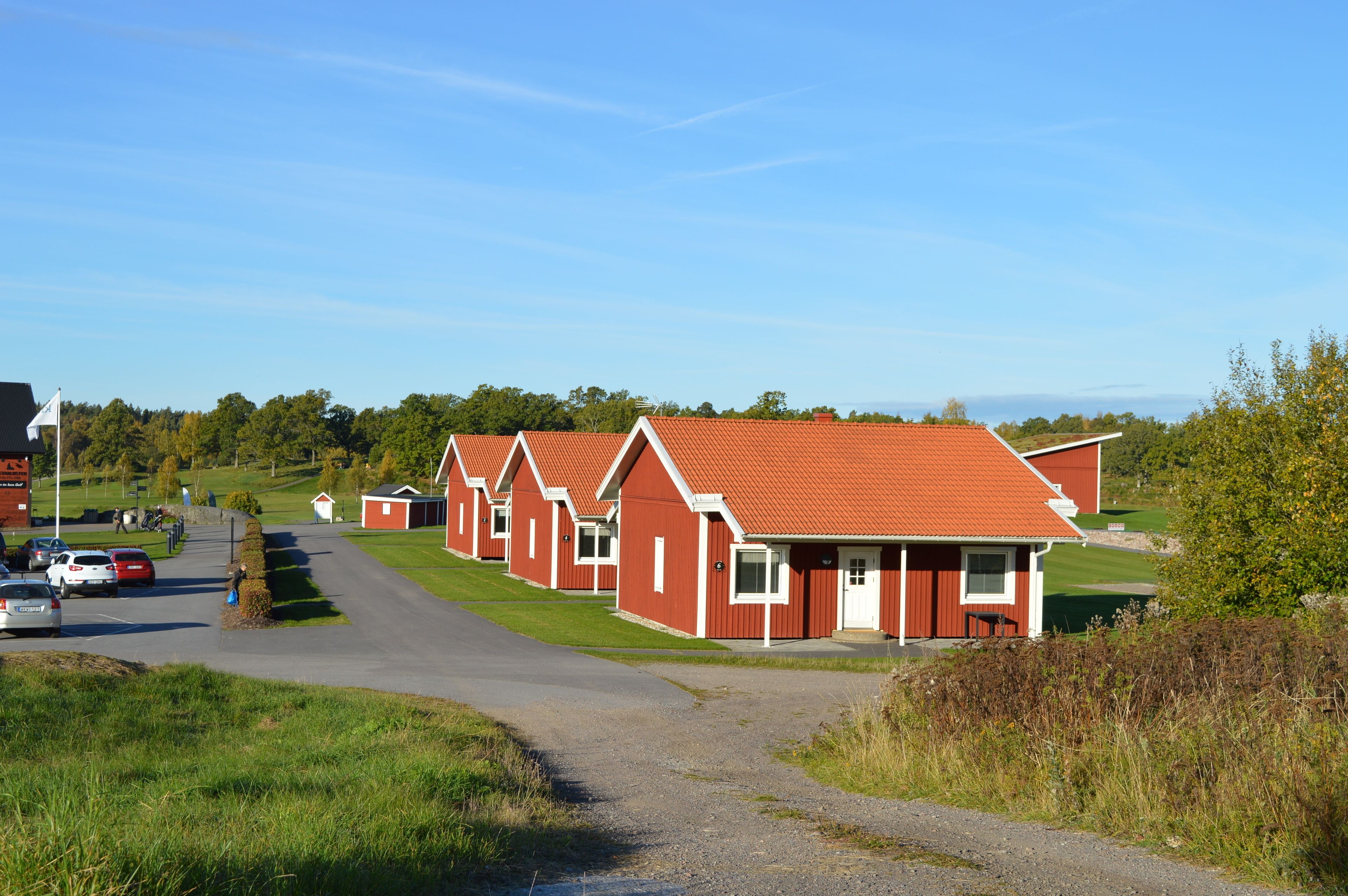 A row of red-roofed cottages with a gravel driveway leading to them.