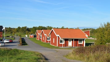 A row of red-roofed cottages with a gravel driveway leading to them.