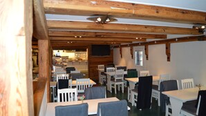 Un restaurant avec des poutres en bois, des tables et des chaises blanches.