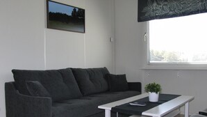 Un salon moderne avec un canapé gris, une table basse blanche et une petite plante en pot.