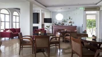 Un amplio vestíbulo de hotel con zona de bar, asientos y ventanas grandes.