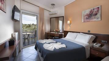 Habitación de hotel con cama, escritorio, silla, balcón y un cuadro en la pared.