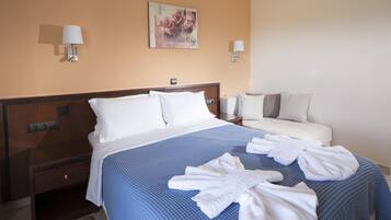 A hotel room with a large bed, a bedside table, a nightstand, a wall-mounted lamp, and a painting on the wall.