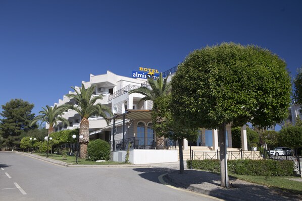 A hotel with a prominent sign, a well-maintained lawn, and a clear sky. - Almira Mare (Chalcis)