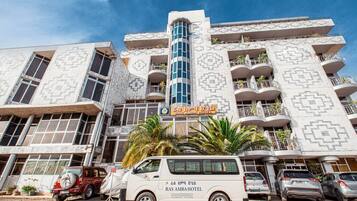 Un edifici de diverses plantes amb façana decorada, balcons i un rètol que anuncia l'Hotel Ras Amba.
