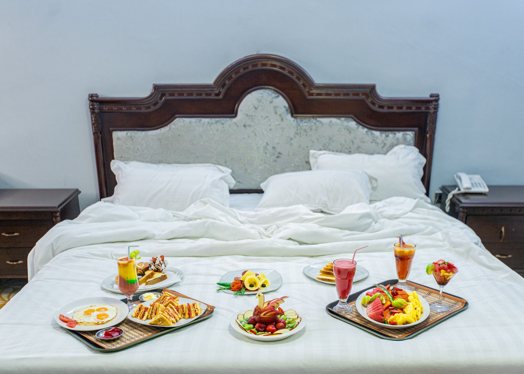 A neatly made bed with white linens and a wooden headboard.
