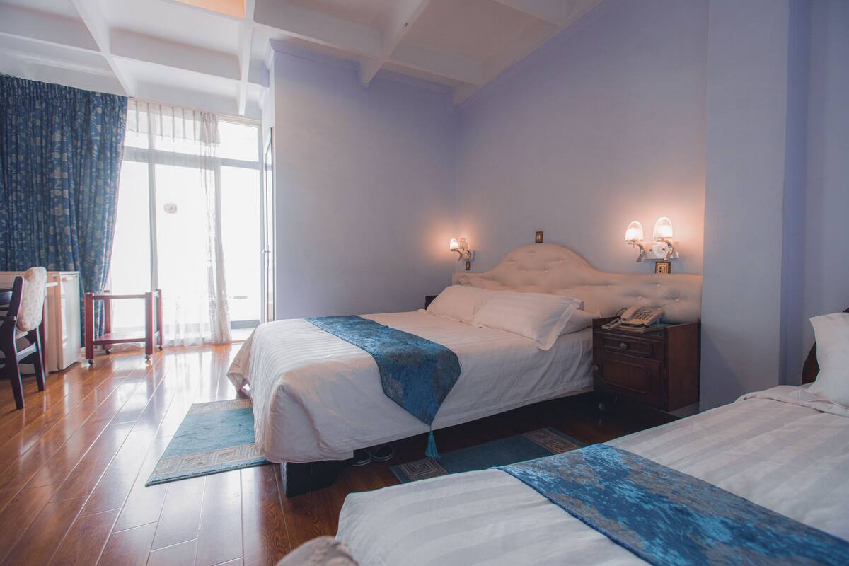 Habitación de hotel con dos camas, un escritorio y una silla.
