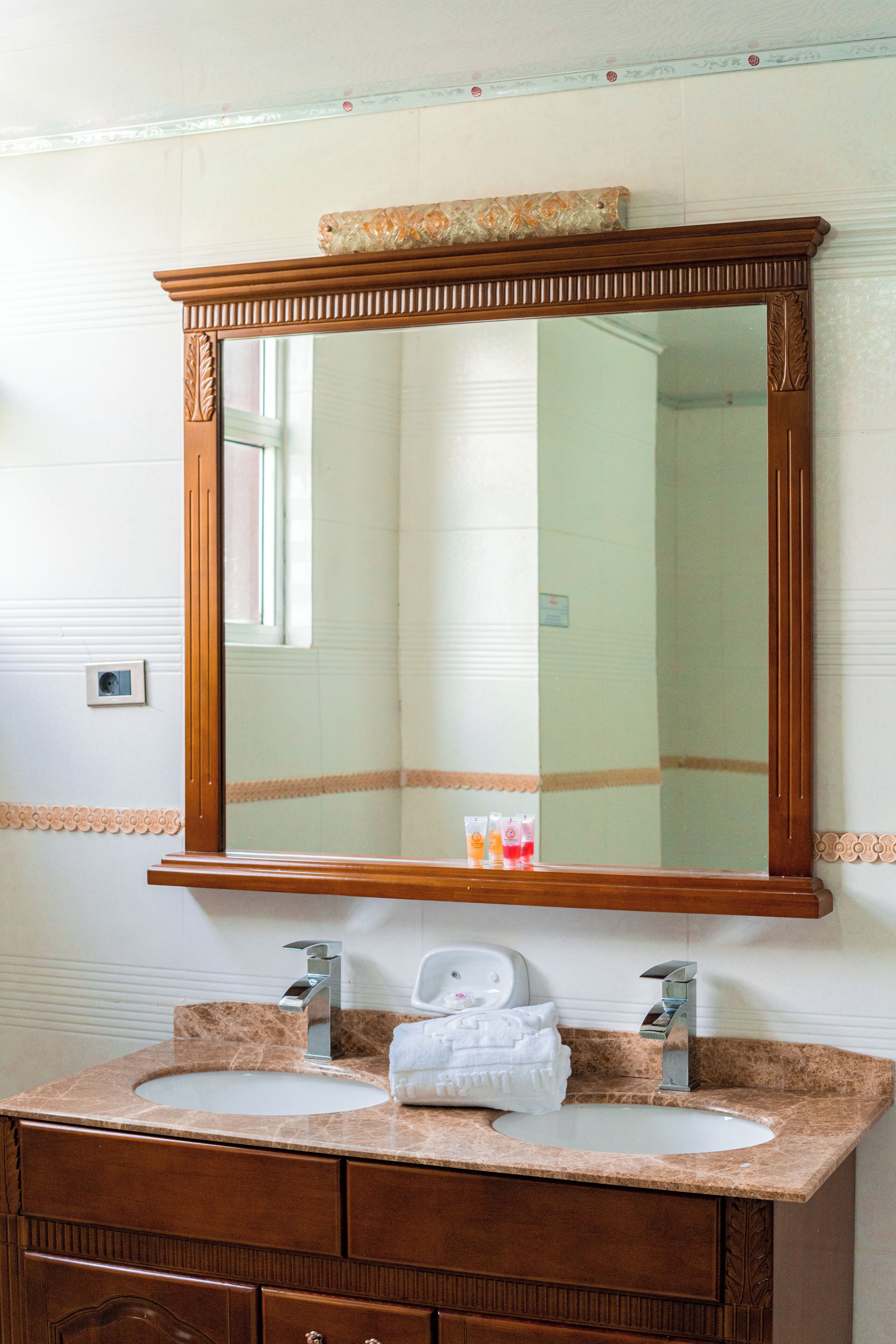 Une salle de bain avec un meuble-lavabo en bois, deux vasques et un grand miroir.