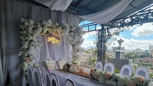 A banquet table set with white chairs, surrounded by floral arrangements and a neon sign. - Ras Amba Hotel (Addis Ababa)