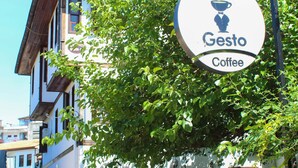 A sign for Gesto Coffee with a clear view of the building's facade and a brick wall. - White City Pension (Antalya)