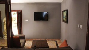 A living room with a flat-screen TV mounted on the wall, a sofa, and a coffee table. - White City Pension (Antalya)