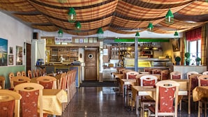 A restaurant with a reception area, wooden chairs, tables, and a ceiling with patterned fabric. - Hotel Alte Post (Kehl)