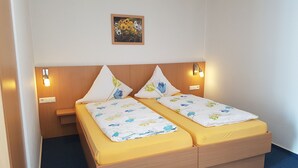 A double bed with floral bedding, wooden headboard, bedside lamps, and a small painting on the wall. - Hotel Alte Post (Kehl)