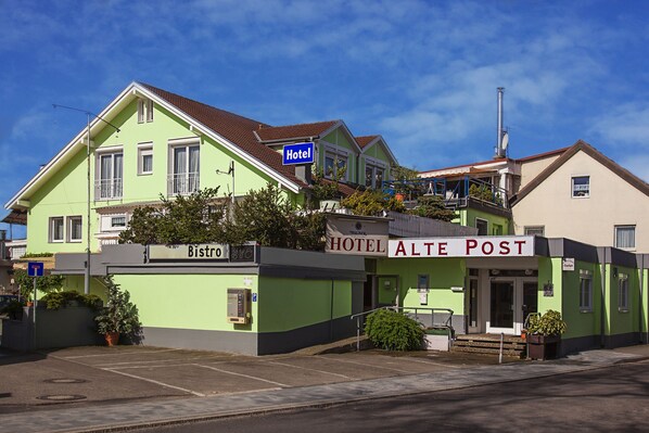 Ein Hotel mit grüner Fassade, einem gut sichtbaren Eingang und einem Schild, das ein Bistro anzeigt.