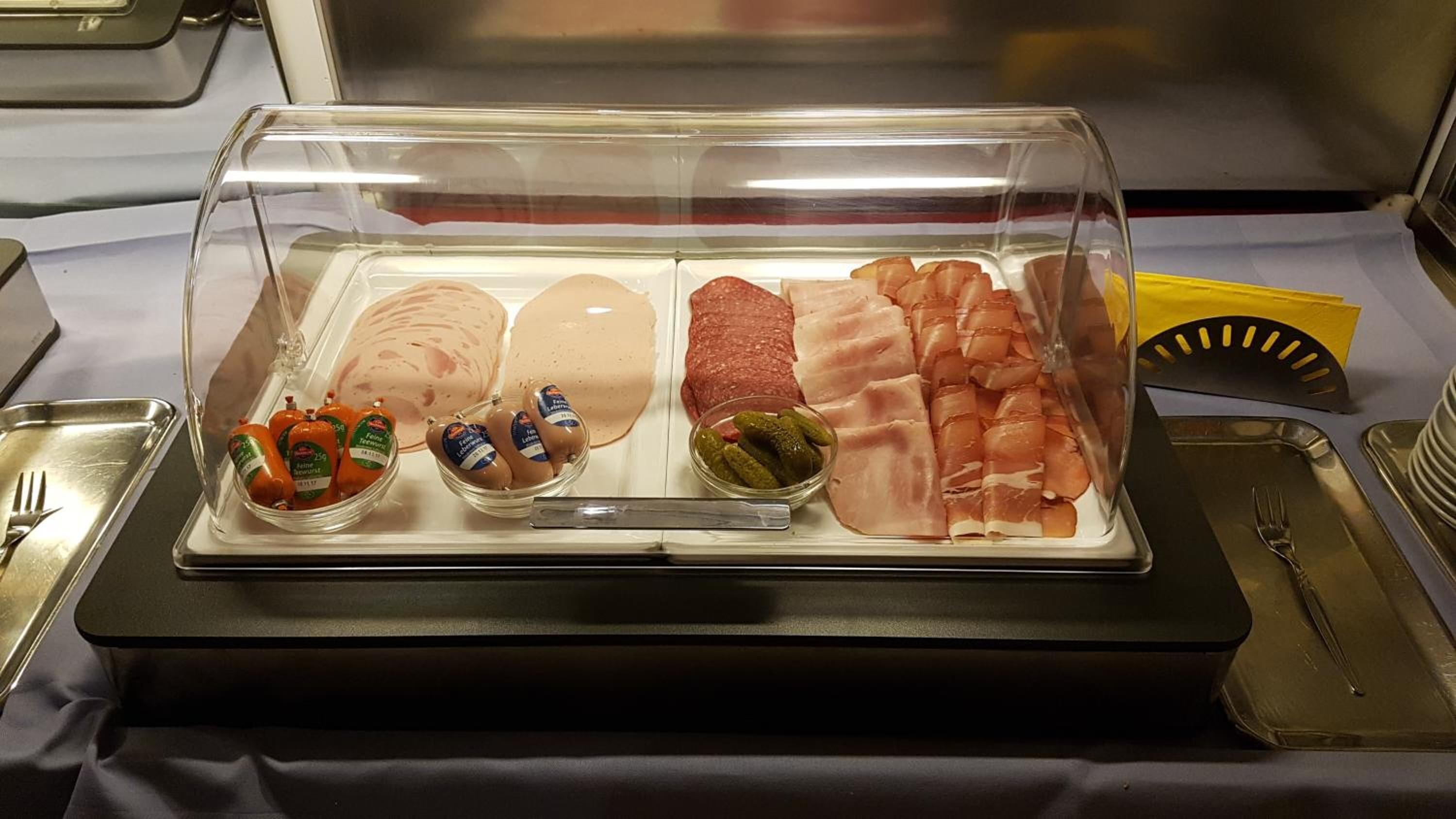 Un buffet con diversi tipi di carne, salsicce e sottaceti.