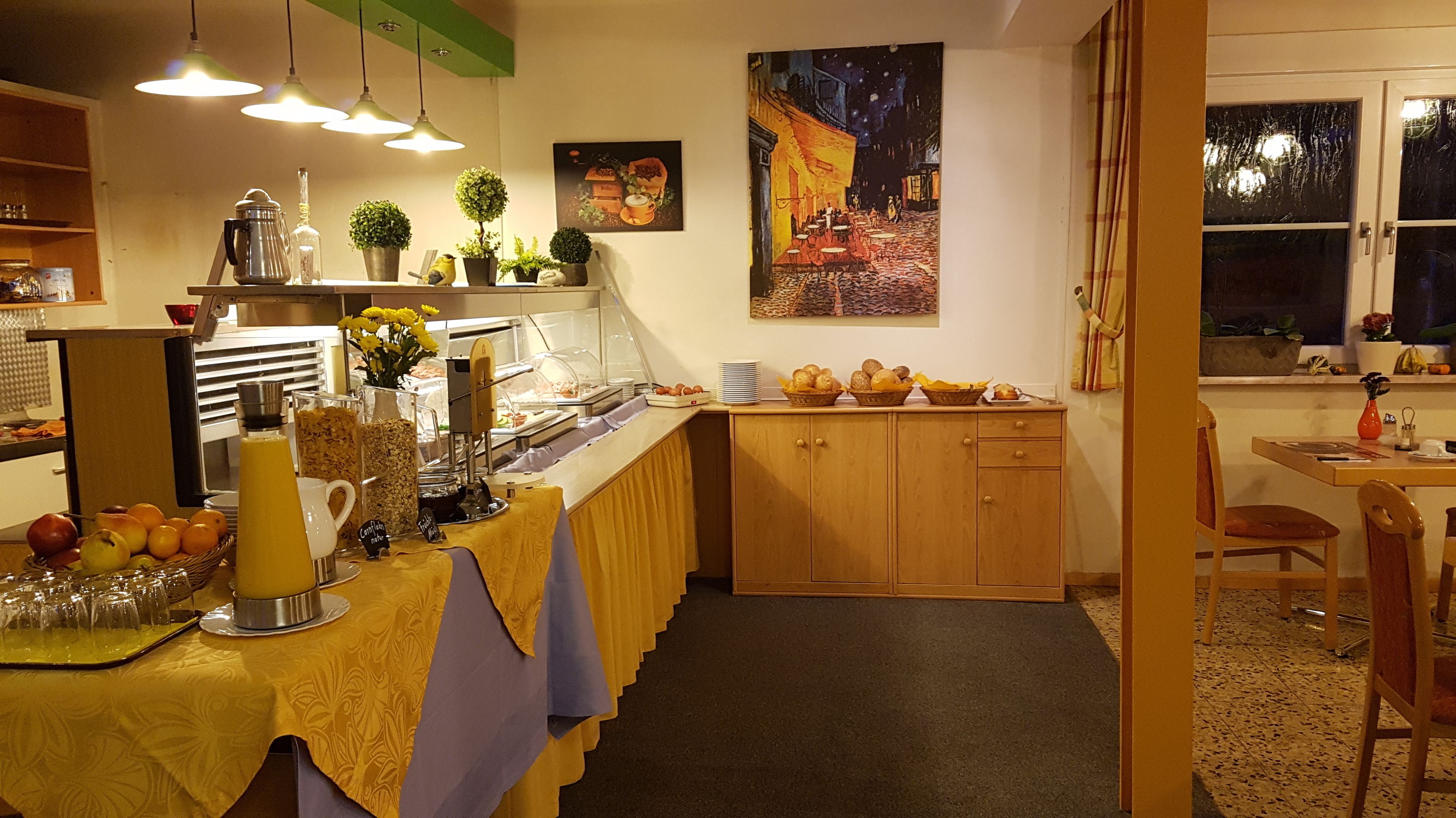 A breakfast buffet setup with a variety of food items and a painting on the wall.