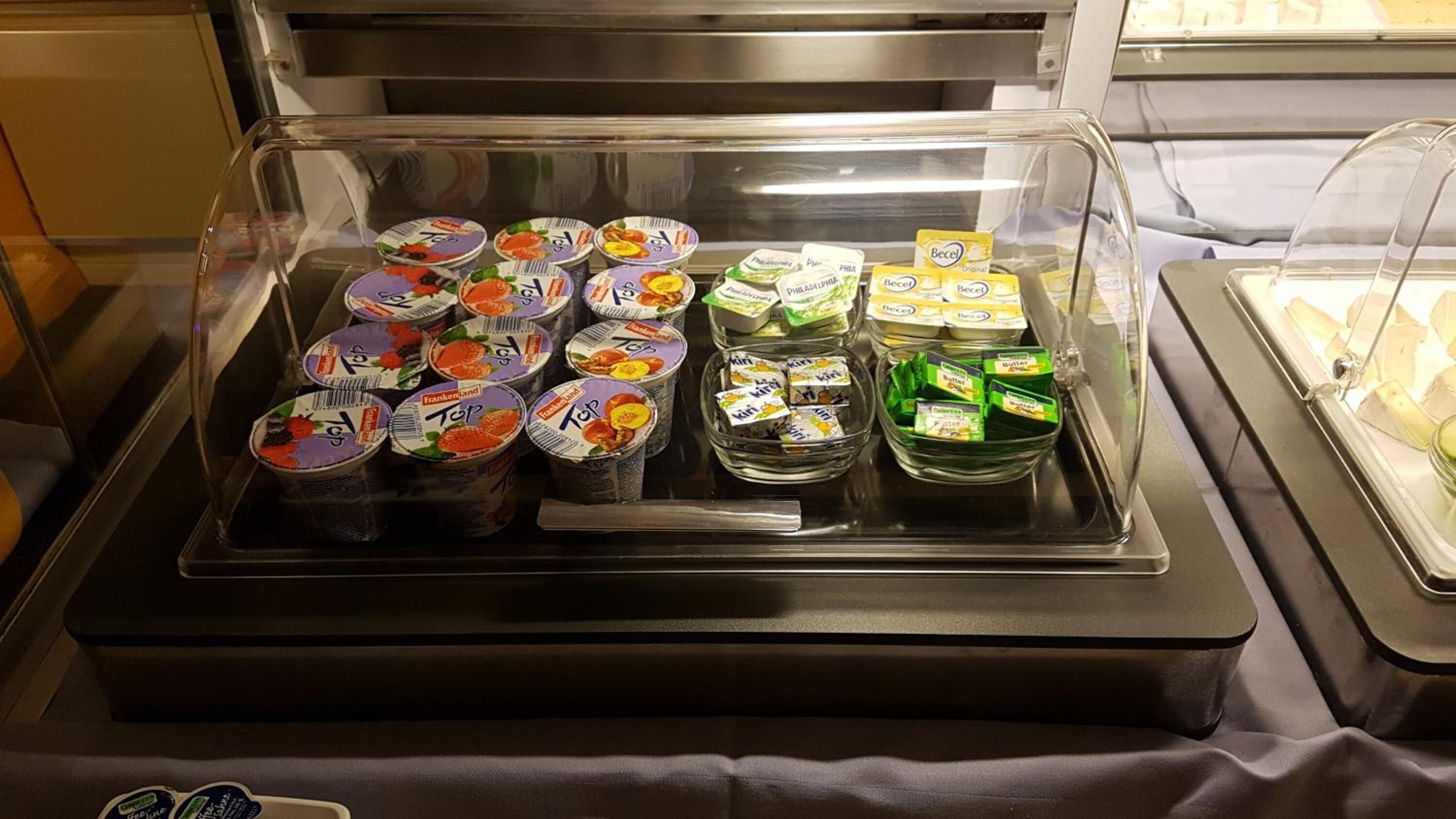 A food display case with various packaged food items, including yogurt and butter.