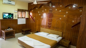 Habitación de hotel con una cama de madera, televisión, pizarra y ventilador de techo.