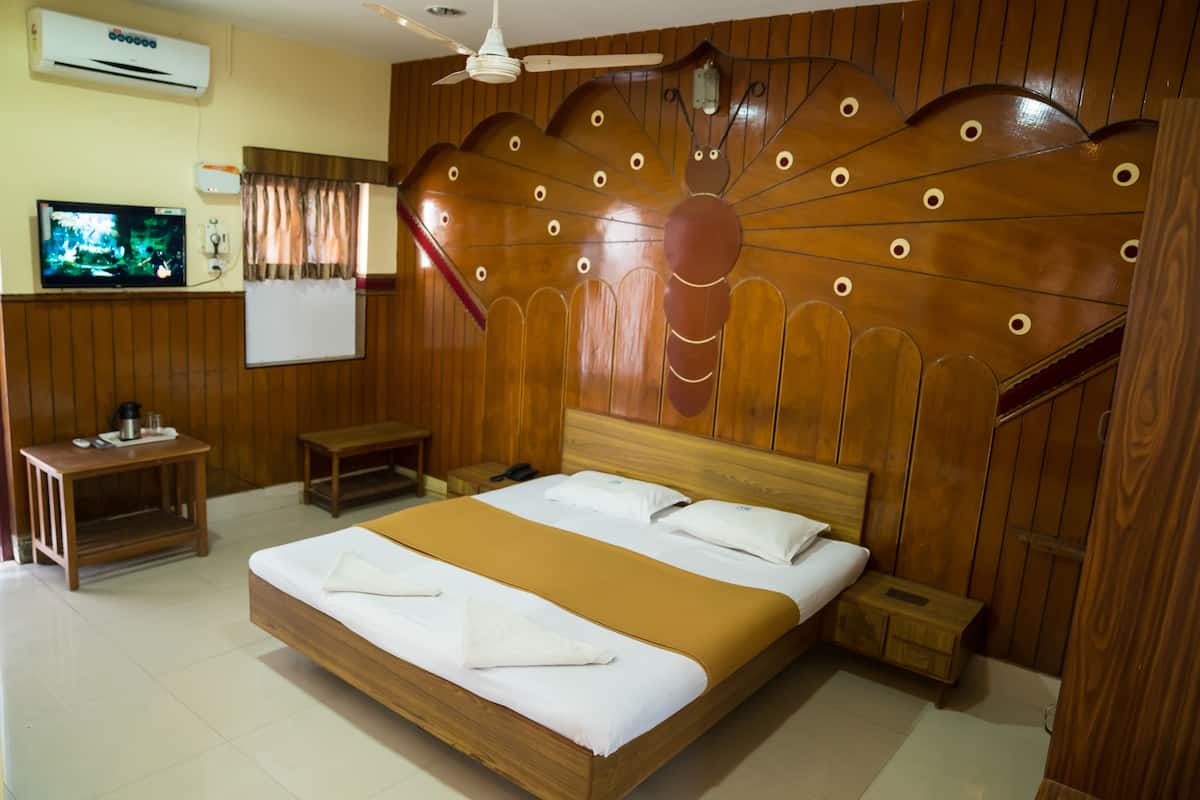 A hotel room with a wooden bed, a television, a whiteboard, and a ceiling fan.