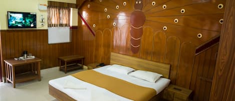 A hotel room with a wooden bed, a television, a whiteboard, and a ceiling fan.
