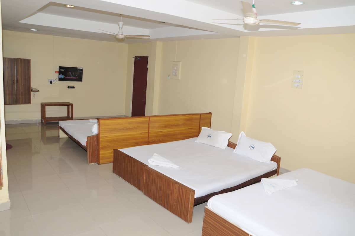 A hotel room with two wooden beds, a television on the wall, and a ceiling fan.