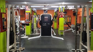 Un gimnasio con varios equipos de ejercicio, incluyendo máquinas de pesas y pesas libres, organizados en un espacio amplio.