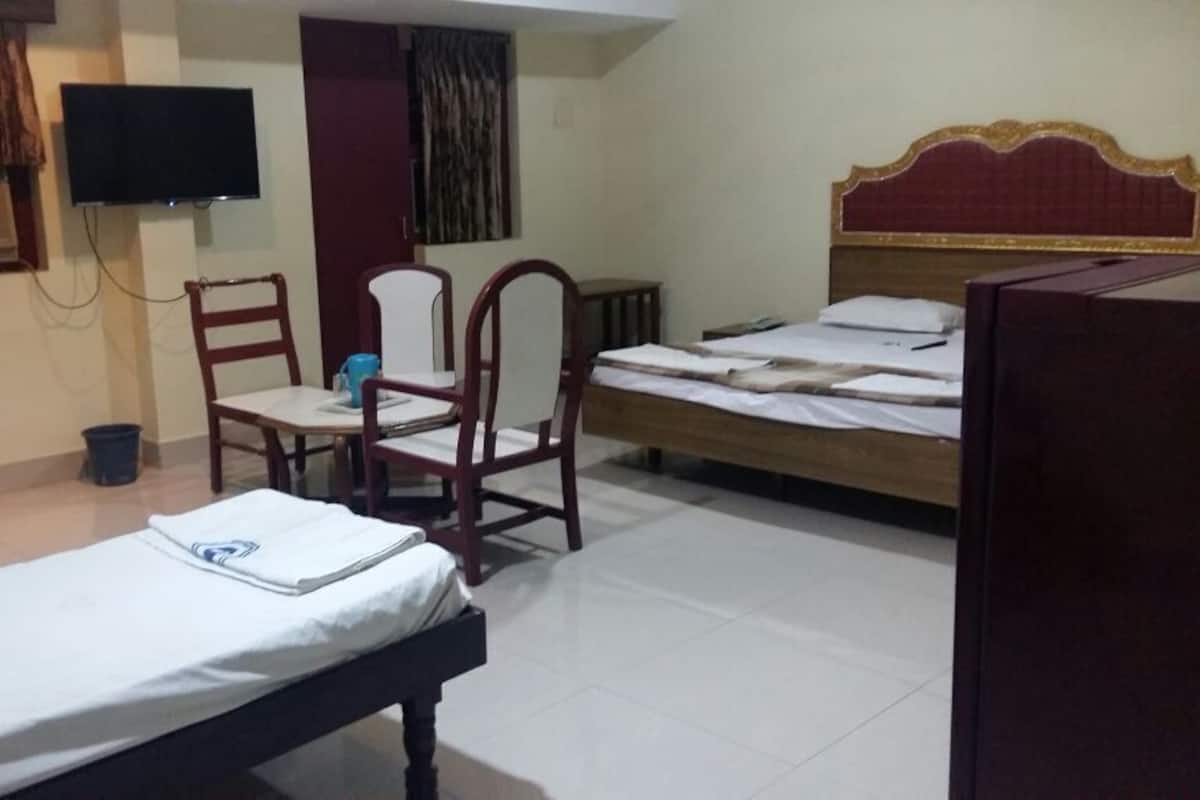 A room with a bed, a desk, a chair, a television, and a window with curtains.