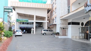 Entrada de hotel con mostrador de recepción, un cartel que dice Hotel Chamma International y un área de estacionamiento.