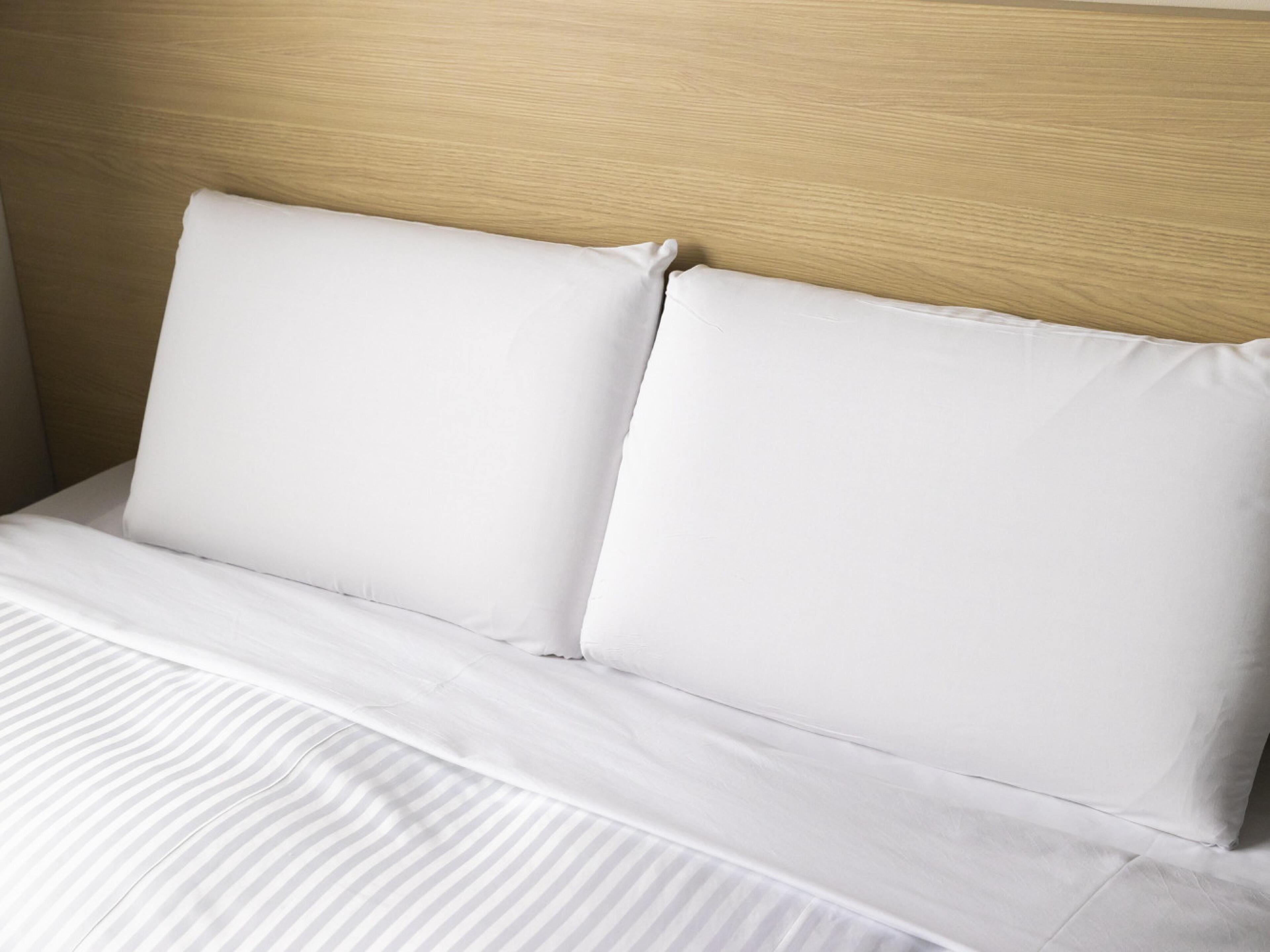 Un lit avec une literie blanche et une tête de lit en bois.