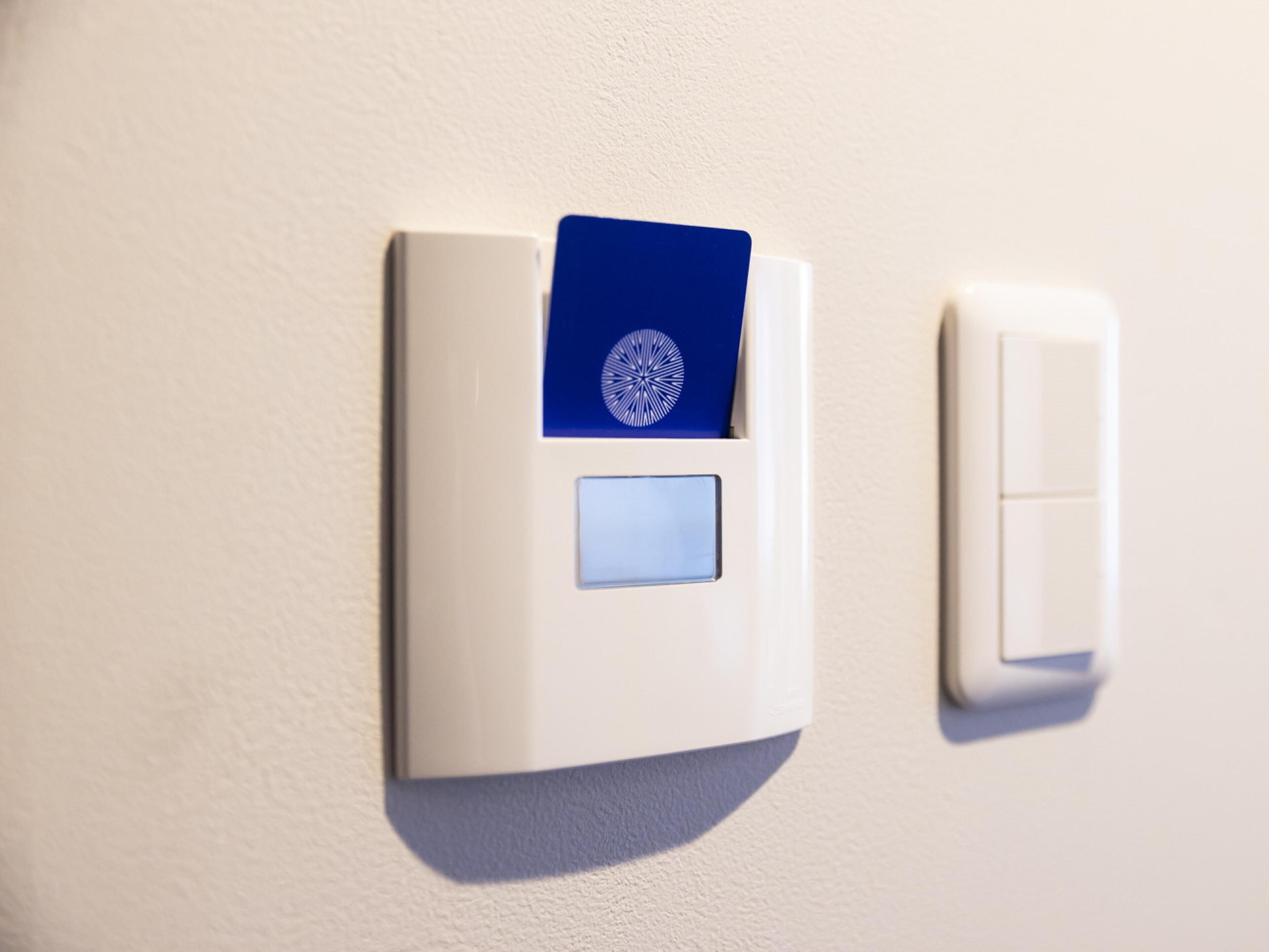 Un thermostat fixé au mur, dans lequel est insérée une carte bleue.