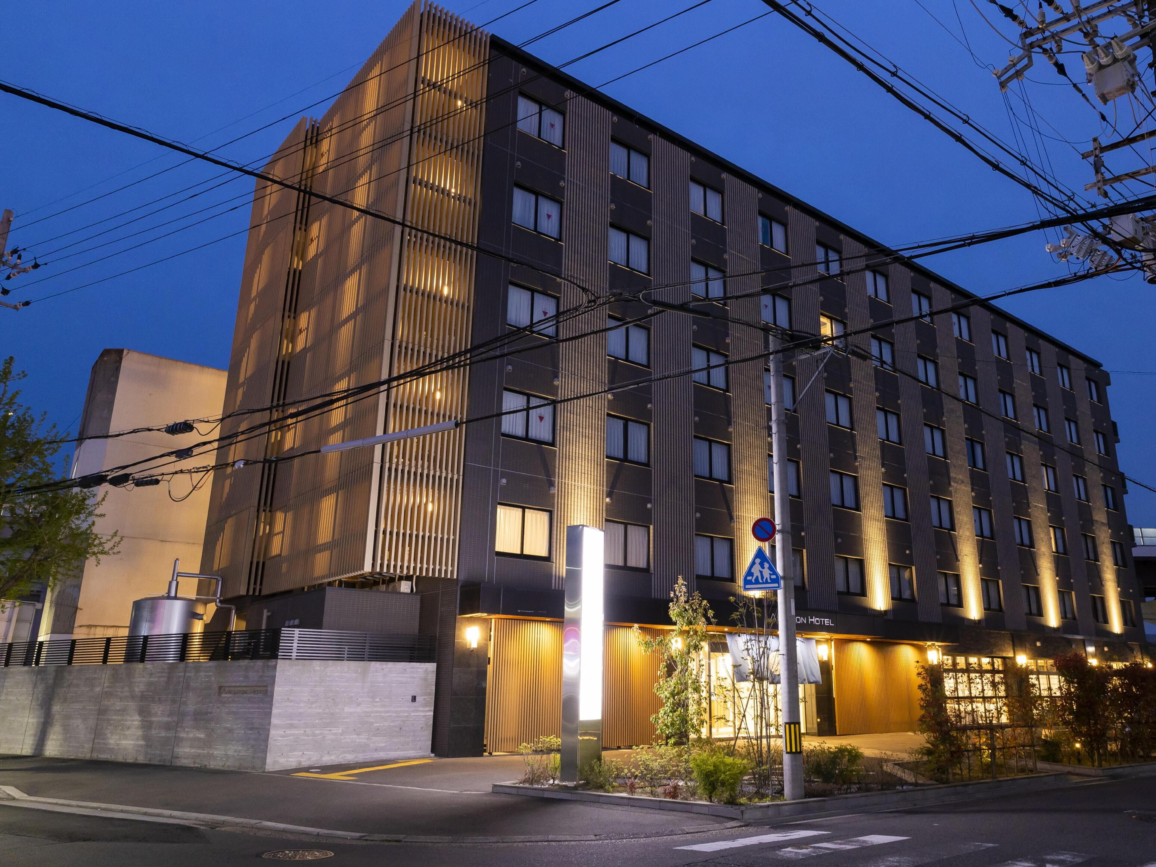 Un hotel moderno con fachada vertical, numerosas ventanas y un letrero que indica una zona de estacionamiento.