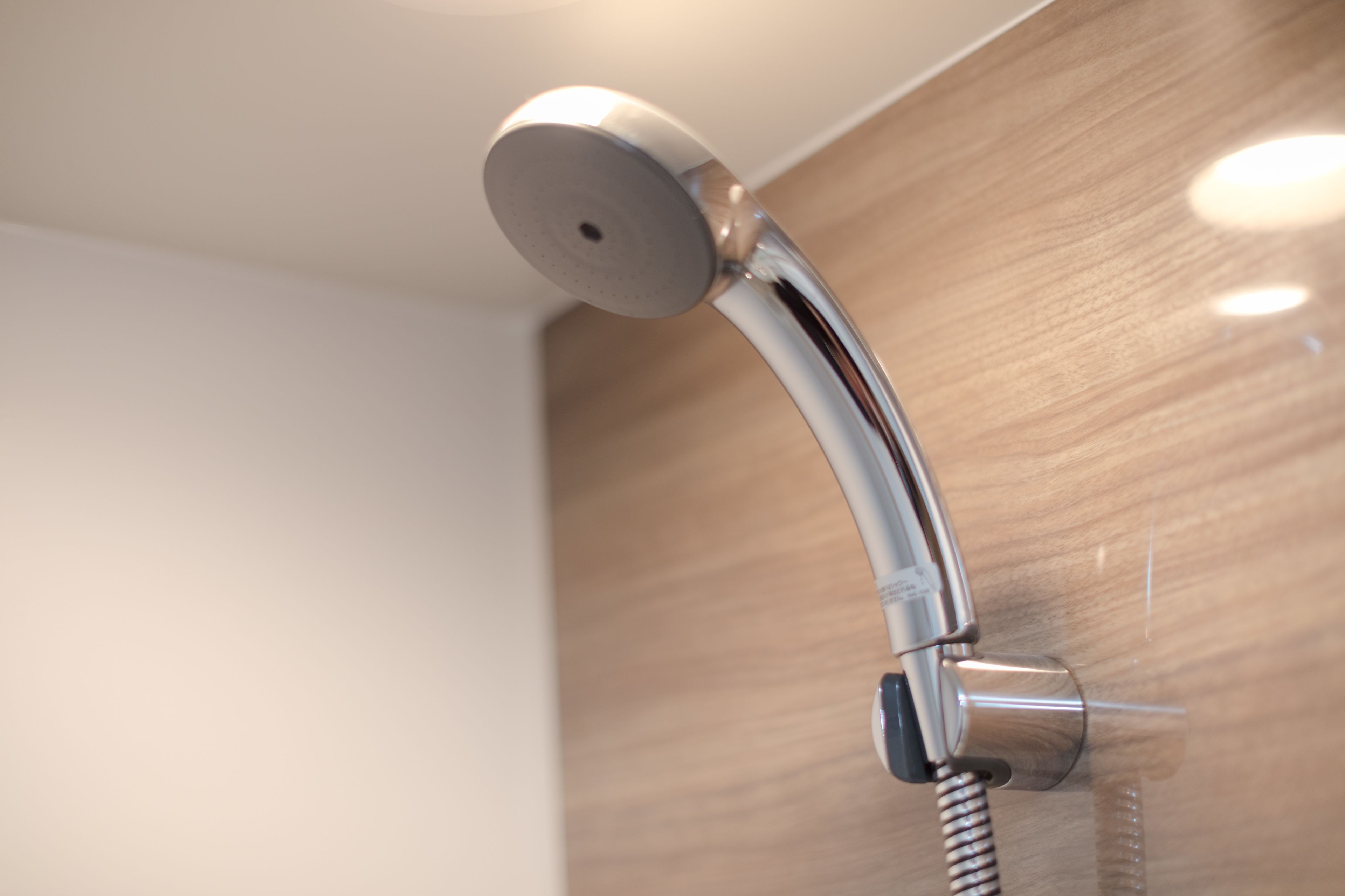 Un cabezal de ducha moderno con manguera flexible, montado en una pared de madera.