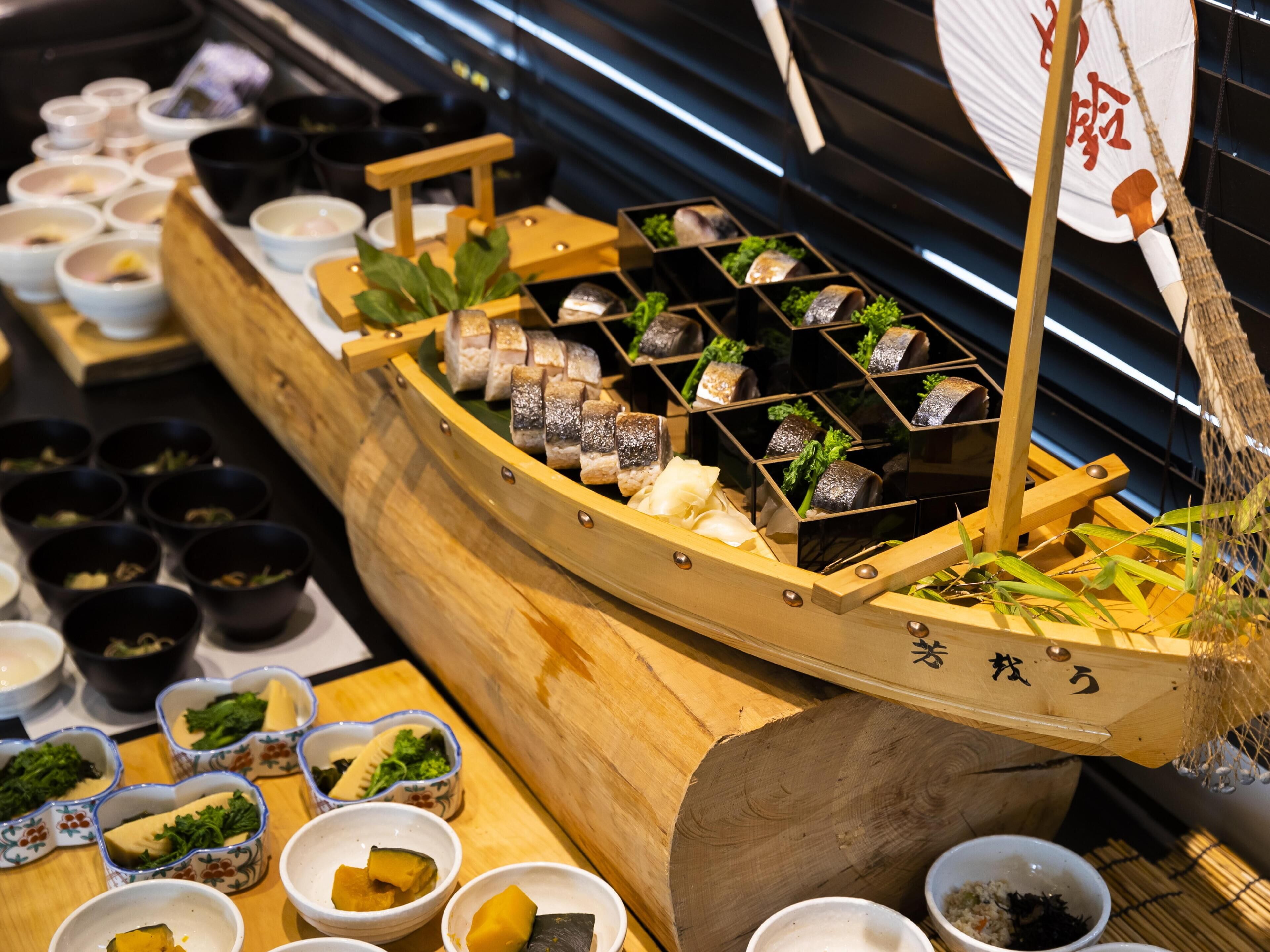 Un bar de sushi con una exhibición de barcos de madera.