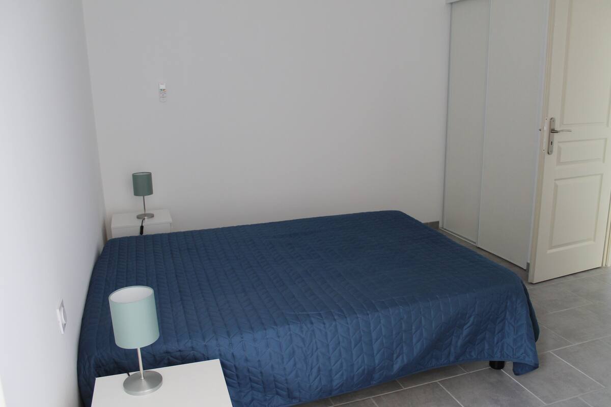 A bedroom with a single bed, a bedside table with a lamp, and a wardrobe.