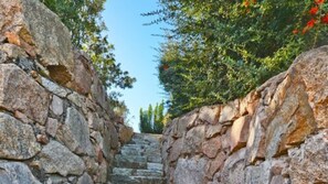 A stone staircase leading upwards, surrounded by stone walls and greenery.