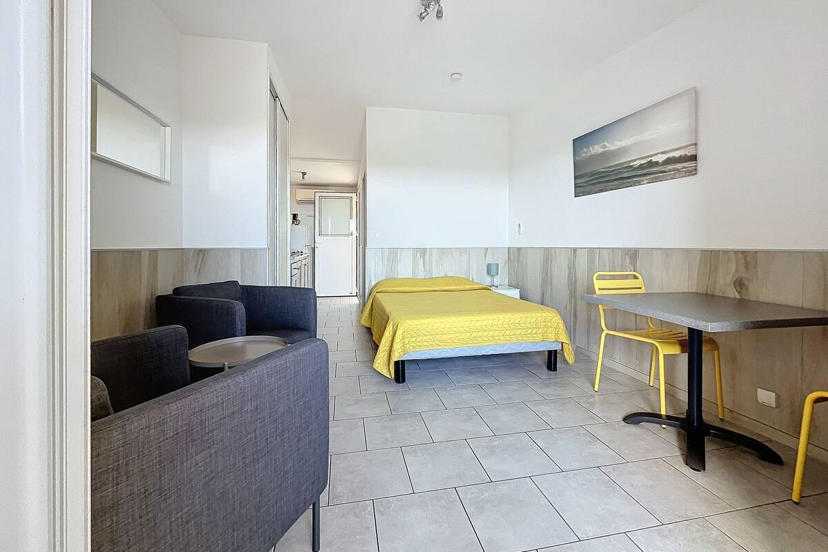 A compact room with a bed, a desk, a chair, and a sofa.
