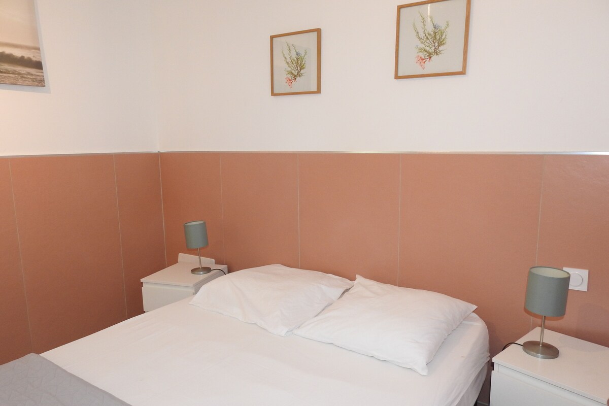 Una habitación de hotel con una cama, dos mesitas de noche y dos lámparas de pared.