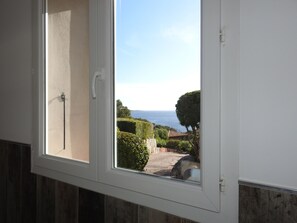 A window with a view of a coastal landscape, including a clear sky and distant horizon.