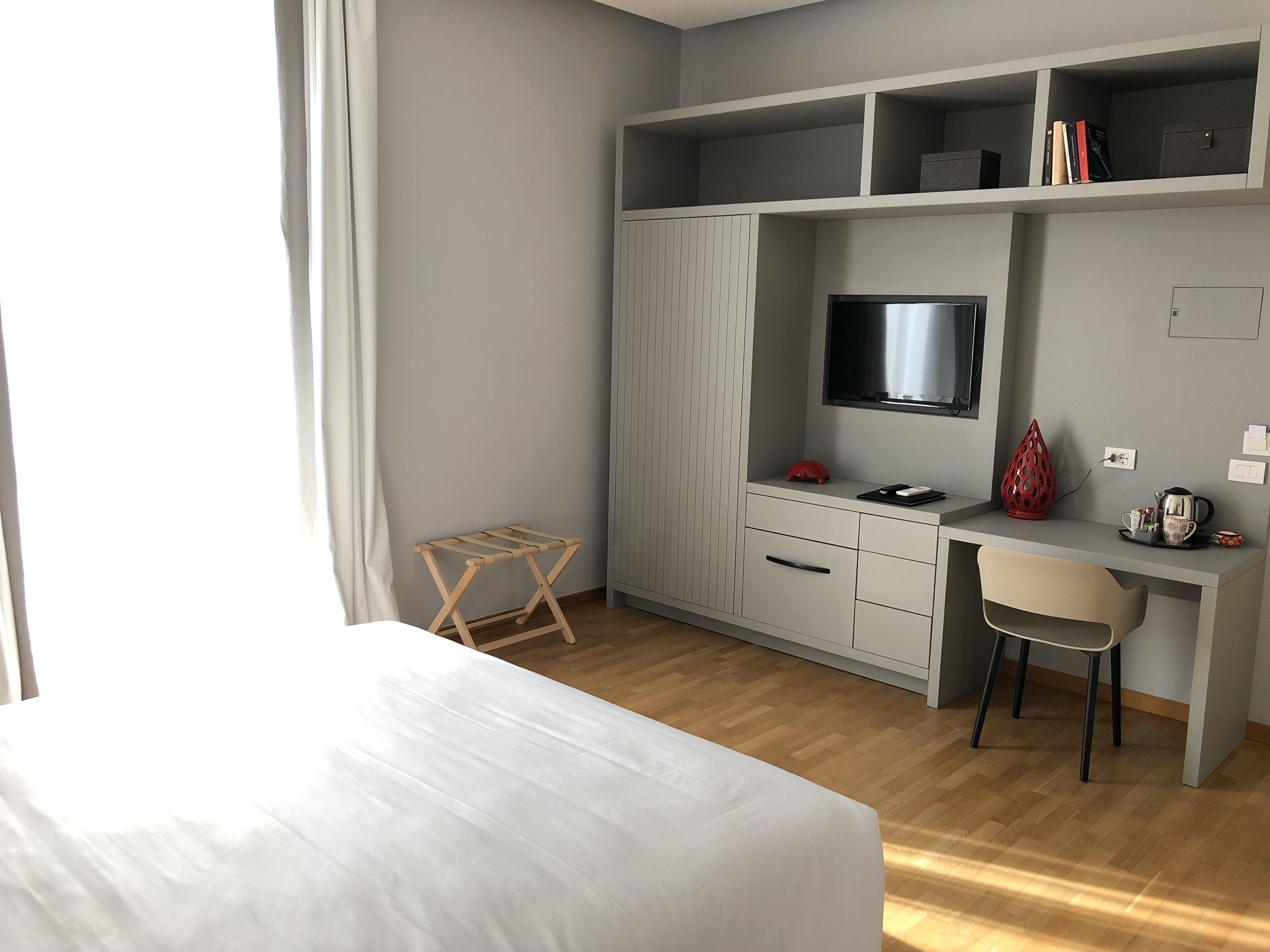 Een hotelkamer met een bed, een bureau met stoel, een televisie en een kledingkast.