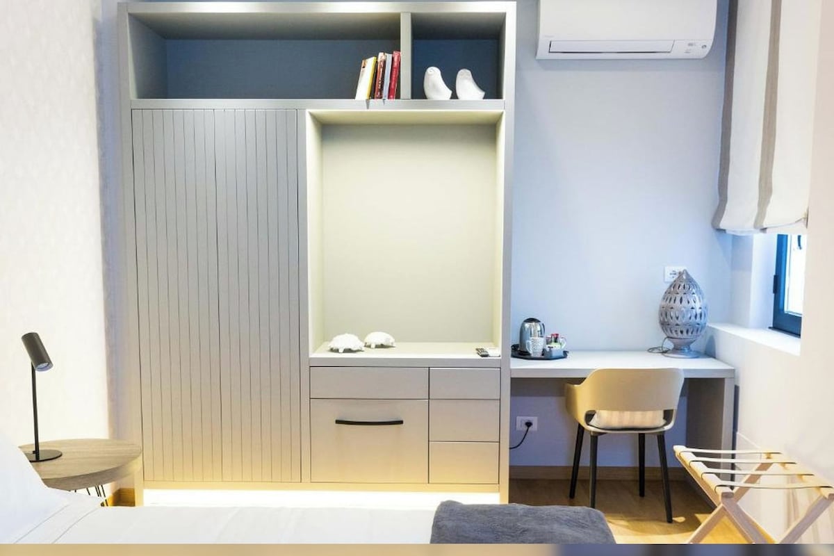 A compact bedroom with a built-in wardrobe, a desk, and a chair.